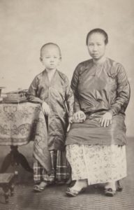 ‘Baju panjang’ met gingham (gestreepte of geruite katoen) sarong (links) en ‘baju kurong’ met batik sarong (rechts). Batavia, 1867. KITLV 87452. Volledige foto: zie onderaan.